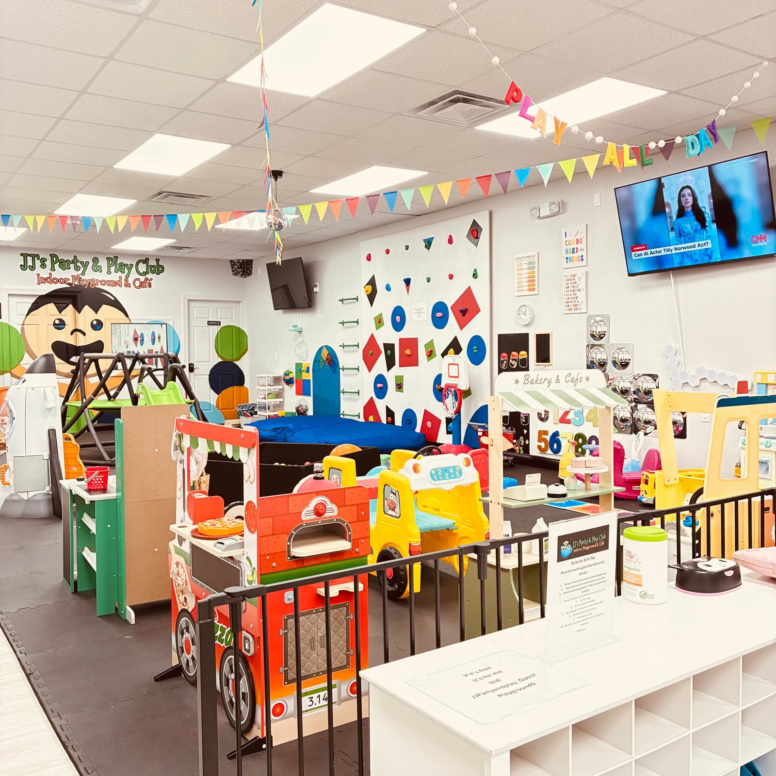 The play floor at JJ's with climbing wall, pretend play stands, and mascot mural
